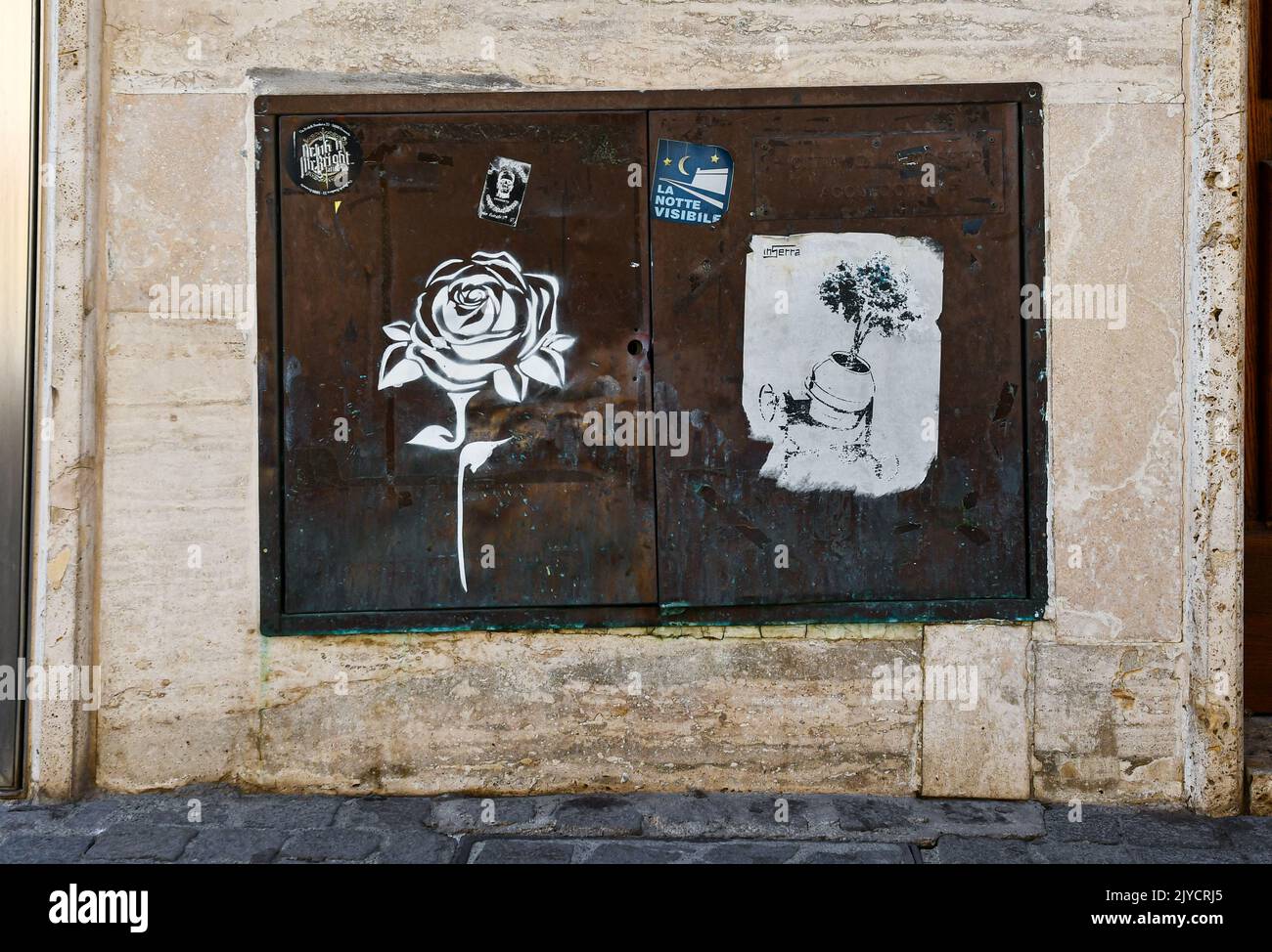 Primo piano di un misuratore di gas arrugginito con stencil e incolla opere d'arte di strada nel centro storico di Grosseto, Toscana, Italia Foto Stock