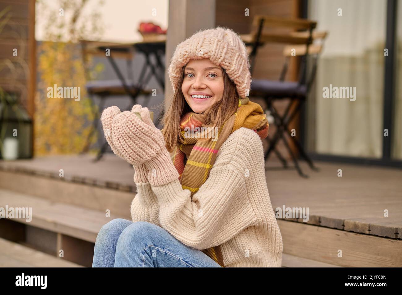 Donna seduta sulla veranda bevendo una bevanda Foto Stock