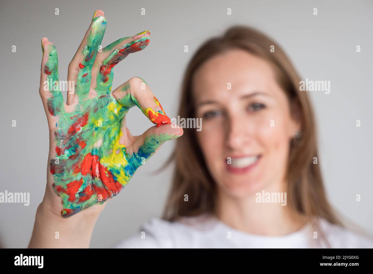 Donna matura esprime sentimenti con OK segno in bianco studio Foto Stock