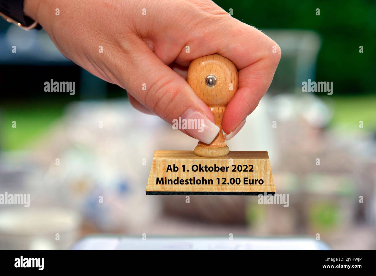 mano della donna con la scritta del francobollo ab 1. Oktober Mindestlohn 12 Euro, nuovo pagamento minimo di 12 €, Germania Foto Stock