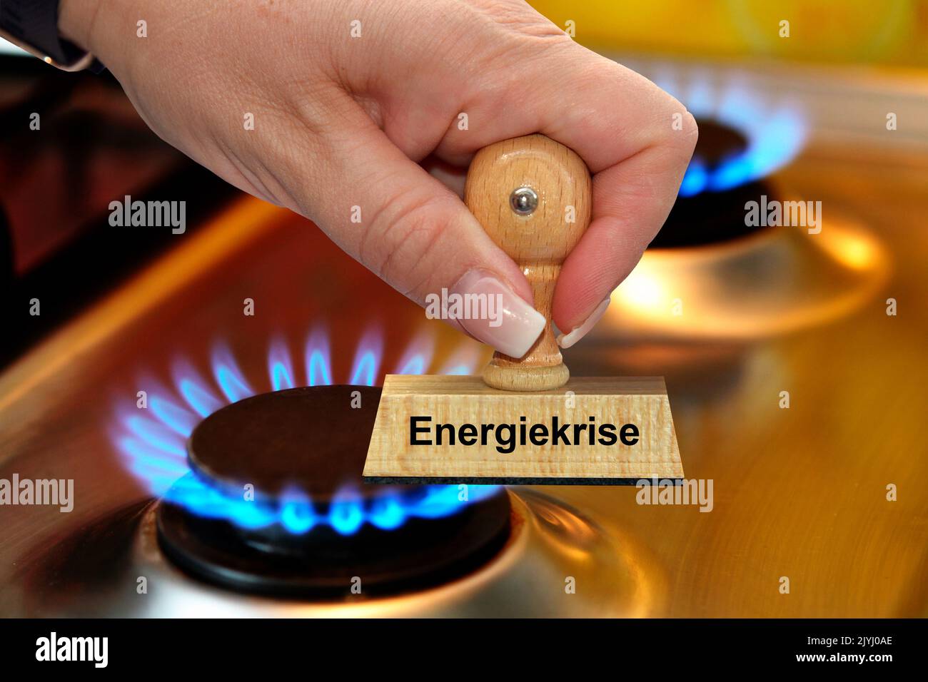 Mano della donna con la scritta del bollo Energiekrise, crisi di energia, fornello a gas sullo sfondo, Germania Foto Stock