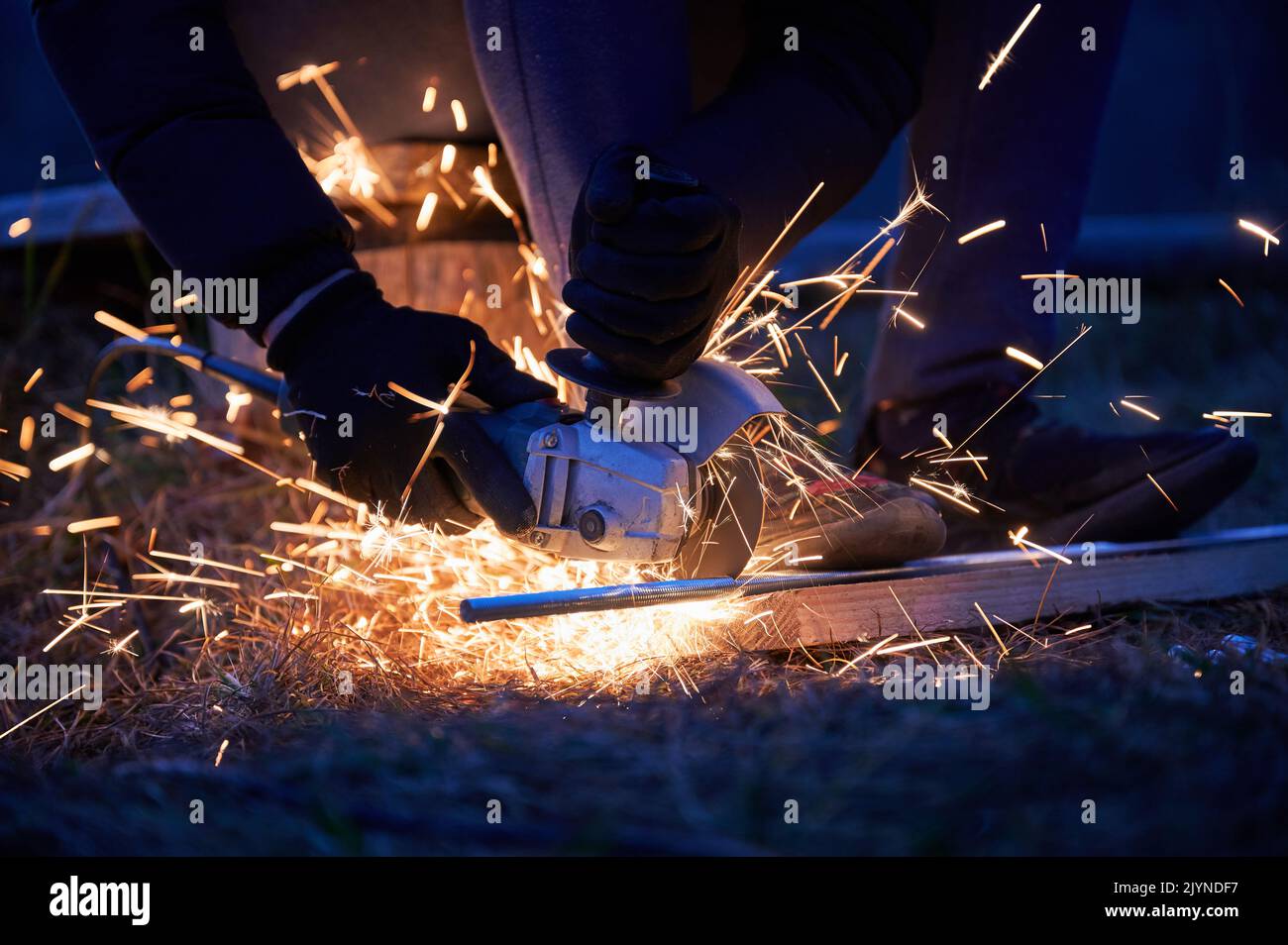 Vista ravvicinata dell'operatore che taglia il metallo, utilizzando la sega circolare di sera. Concetto di costruzione. Foto Stock