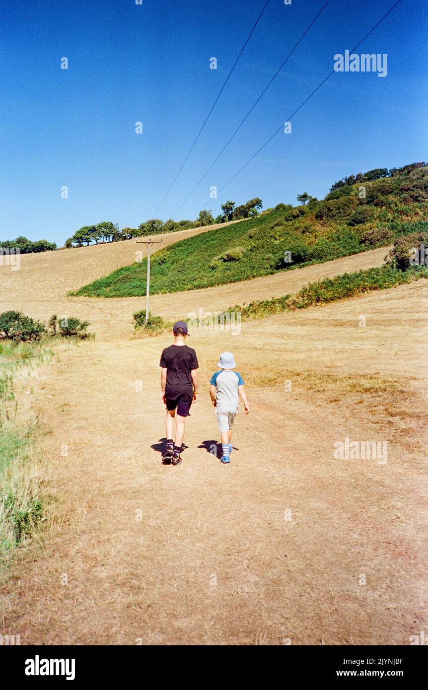 Fratelli Holing mani che camminano attraverso un campo, Hope Cove, Kingsbridge, South Devon, Inghilterra, Regno Unito. Foto Stock