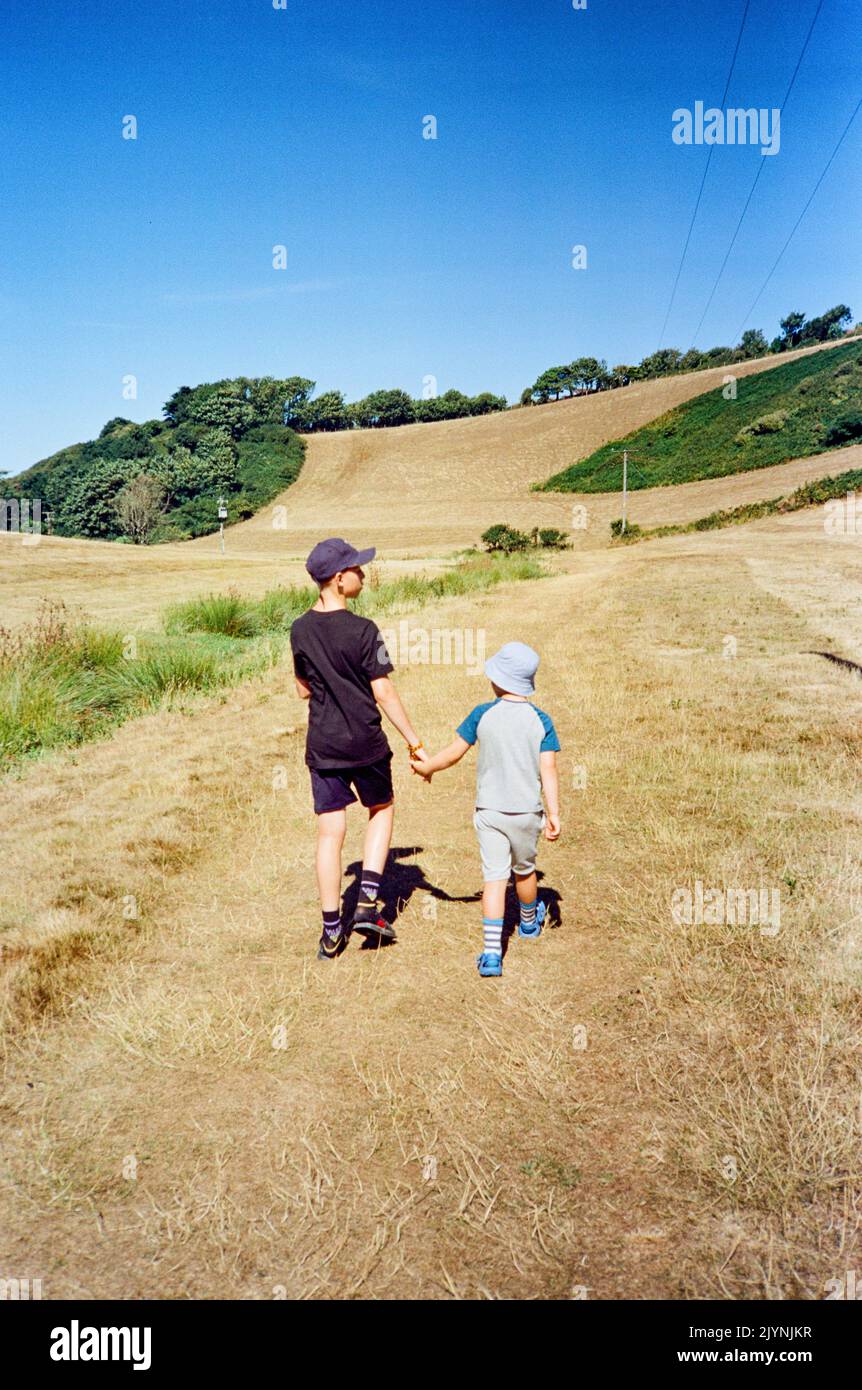Fratelli Holing mani che camminano attraverso un campo, Hope Cove, Kingsbridge, South Devon, Inghilterra, Regno Unito. Foto Stock