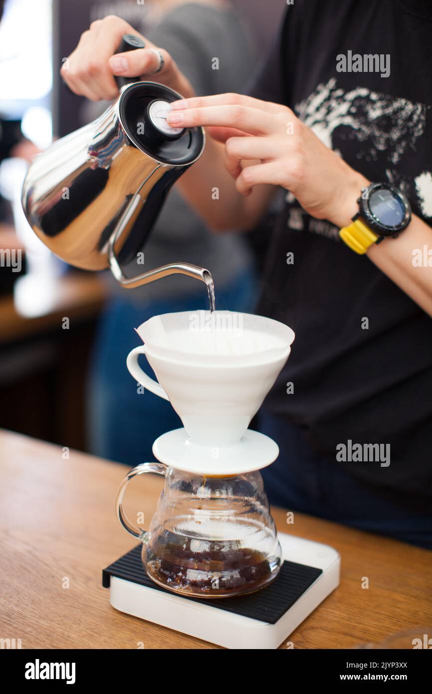 il barista versa l'acqua dal bollitore Foto Stock