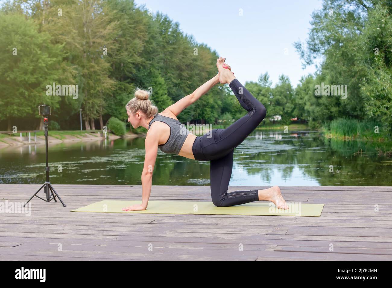 Una donna in un su una piattaforma di legno in estate, fa yoga Foto Stock