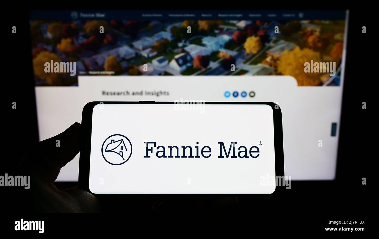 Persona in possesso di smartphone con il logo della società finanziaria americana Fannie Mae (FNMA) sullo schermo di fronte al sito web. Messa a fuoco sul display del telefono. Foto Stock