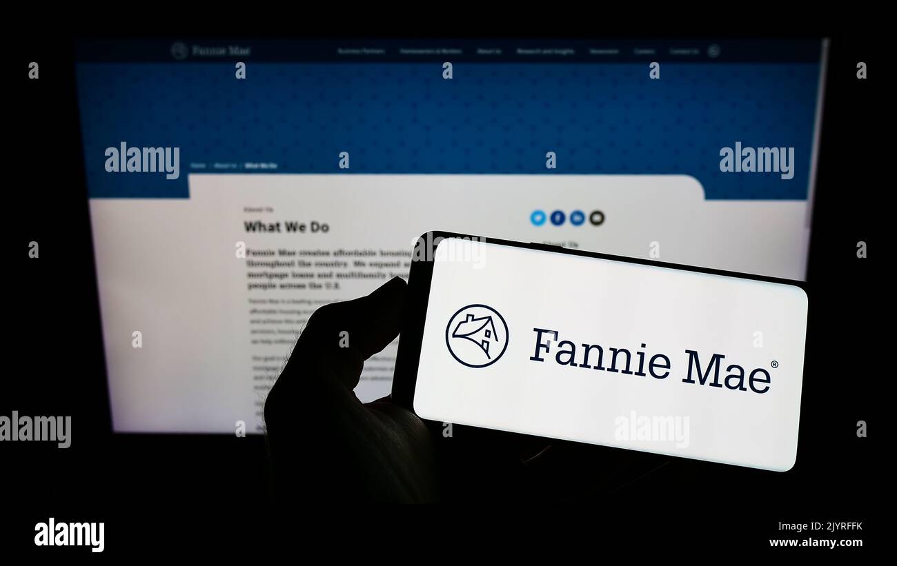 Persona che tiene il telefono mobile con il logo della società finanziaria americana Fannie Mae (FNMA) sullo schermo di fronte alla pagina web. Messa a fuoco sul display del telefono. Foto Stock