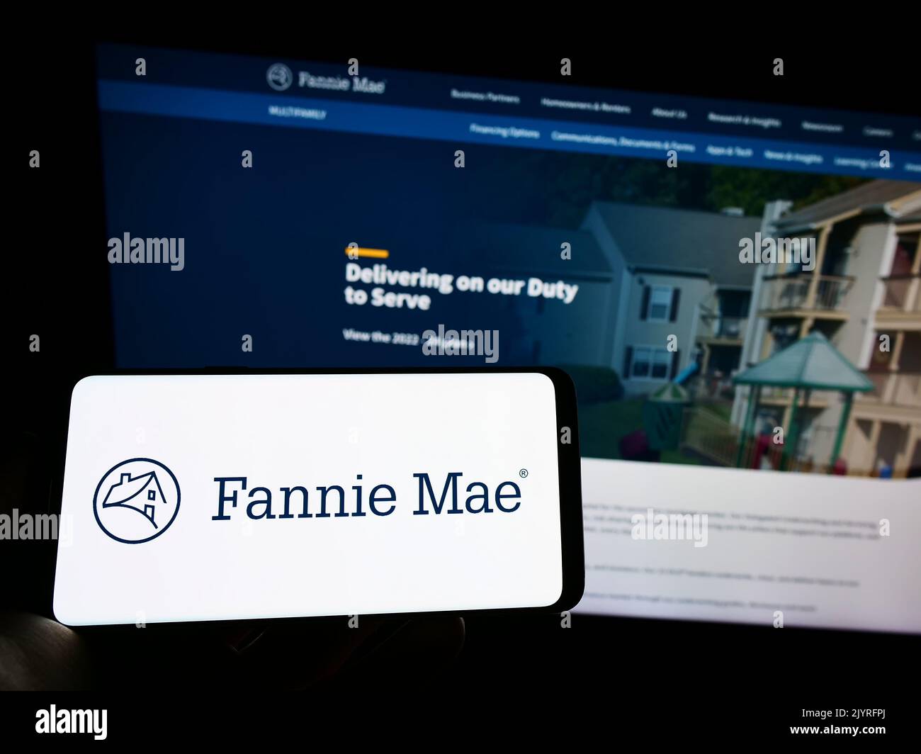 Persona che tiene il cellulare con il logo della società finanziaria americana Fannie Mae (FNMA) sullo schermo di fronte al sito web aziendale. Messa a fuoco sul display del telefono. Foto Stock