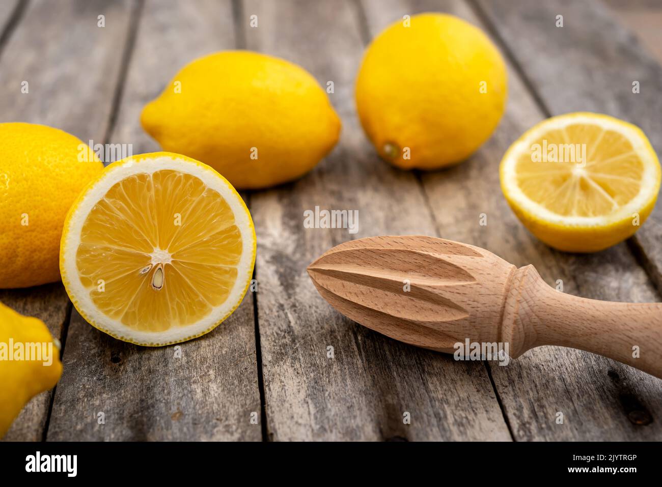 Limoni freschi e spremiagrumi in legno su un tavolo rustico. Messa a fuoco selettiva. Foto Stock