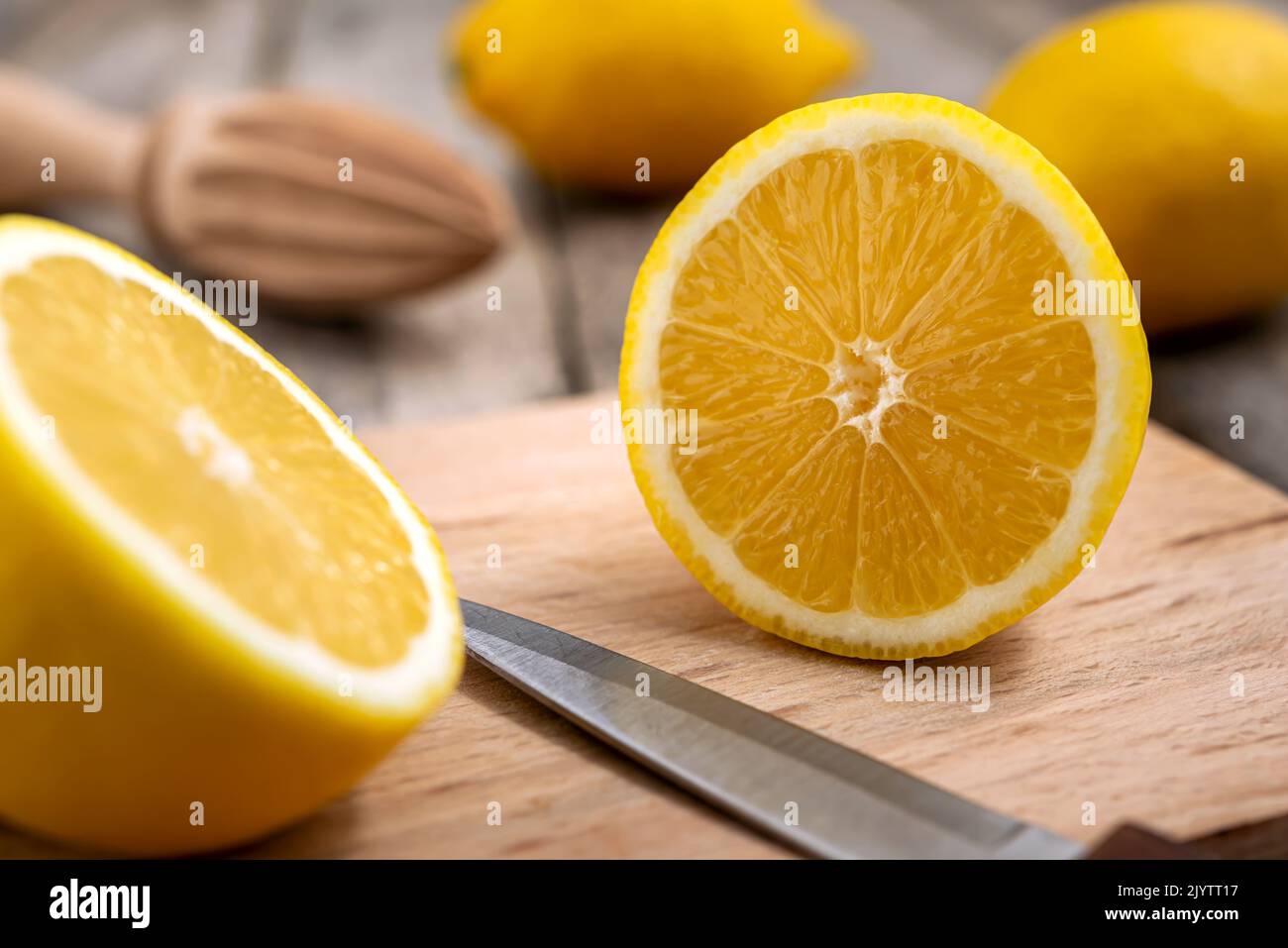 Limone fresco tagliato a metà con coltello su tagliere di legno. Foto Stock
