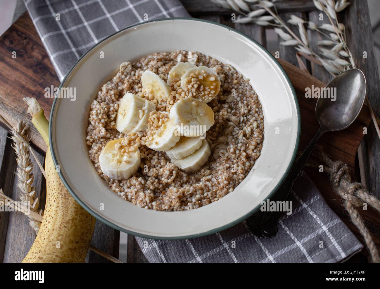 Colazione porridge di cereali con avena, amaranto, quinoa e banane, noci e sciroppo d'acero Foto Stock