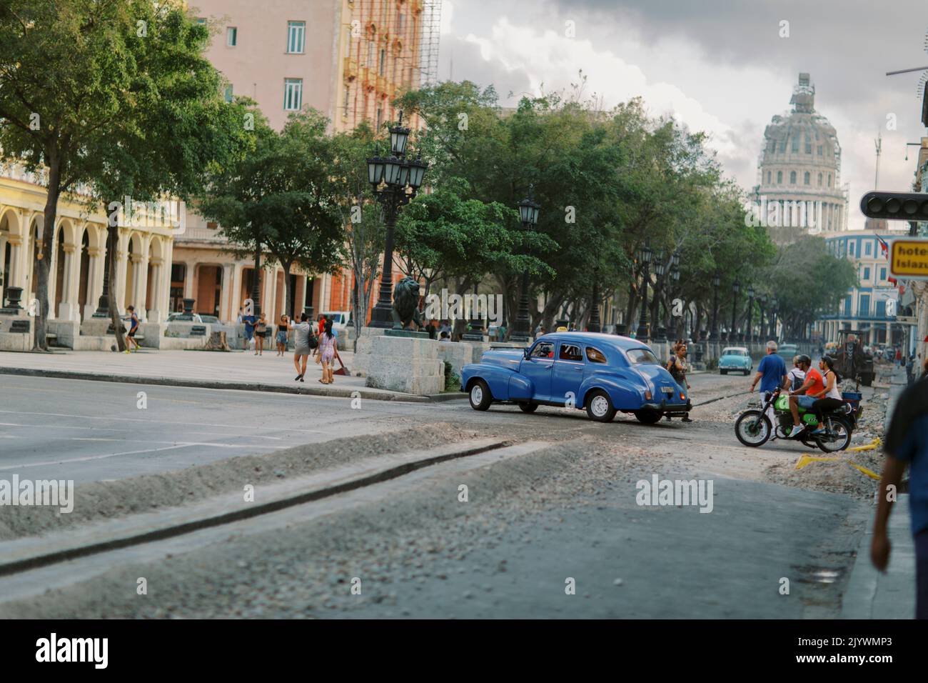 Auto d'epoca blu e moto che attraversano la piazza della città sotto co Foto Stock