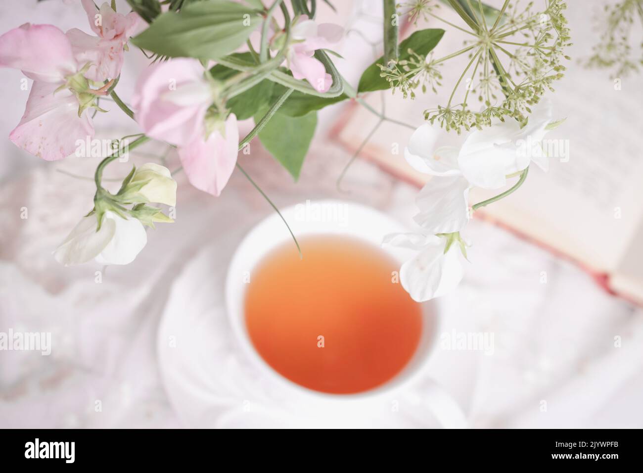 Una tazza bianca di tè e fiori di piselli Foto Stock