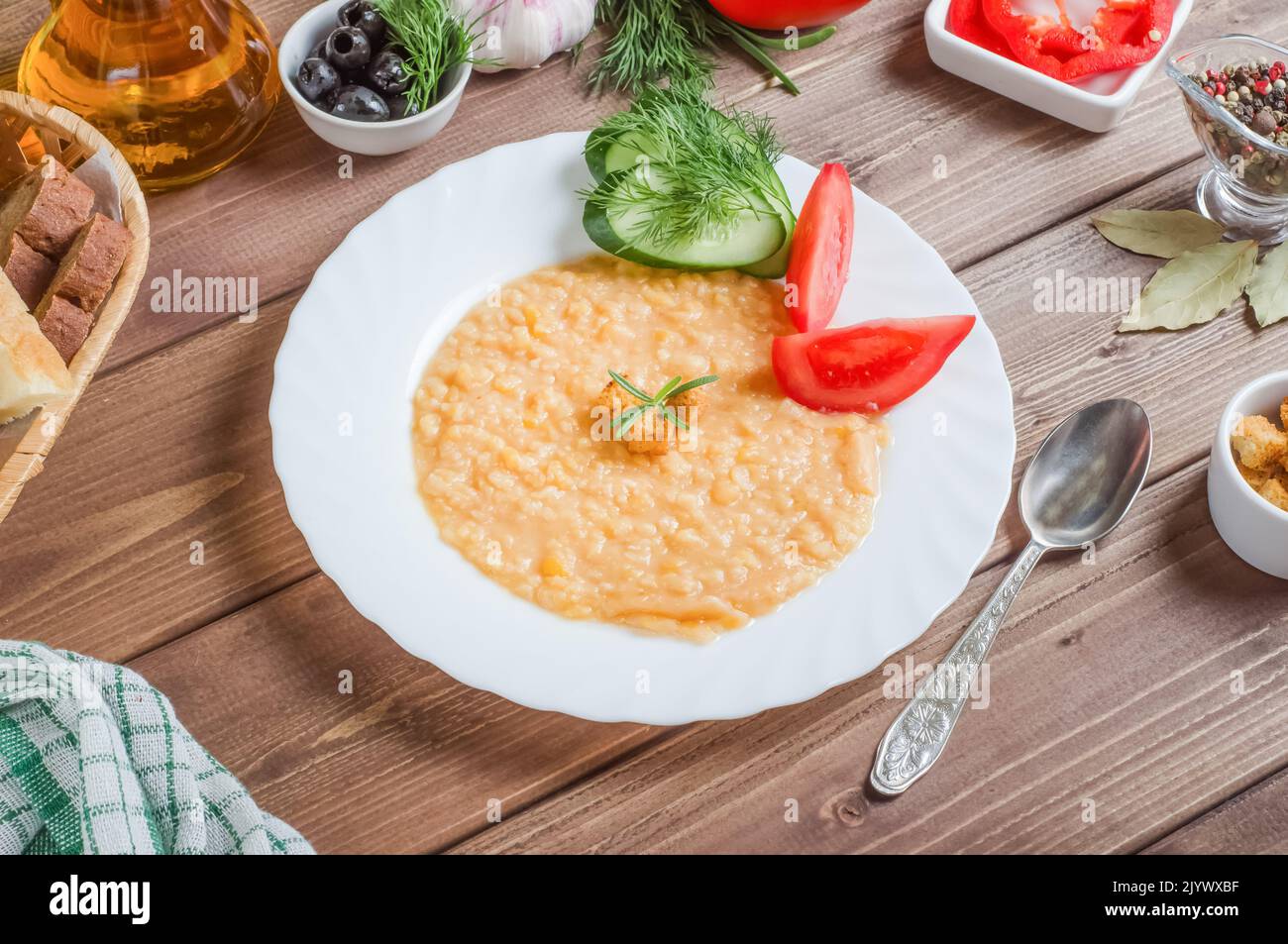 Delizioso porridge di piselli appetitoso guarnire con verdure fresche su un piatto bianco su uno sfondo di legno Foto Stock