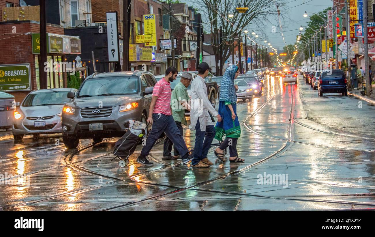 Persone che camminano per strada in un giorno di pioggia tempo. Folla di persone che attraversano una strada piovosa della città, Toronto, Canada Foto Stock