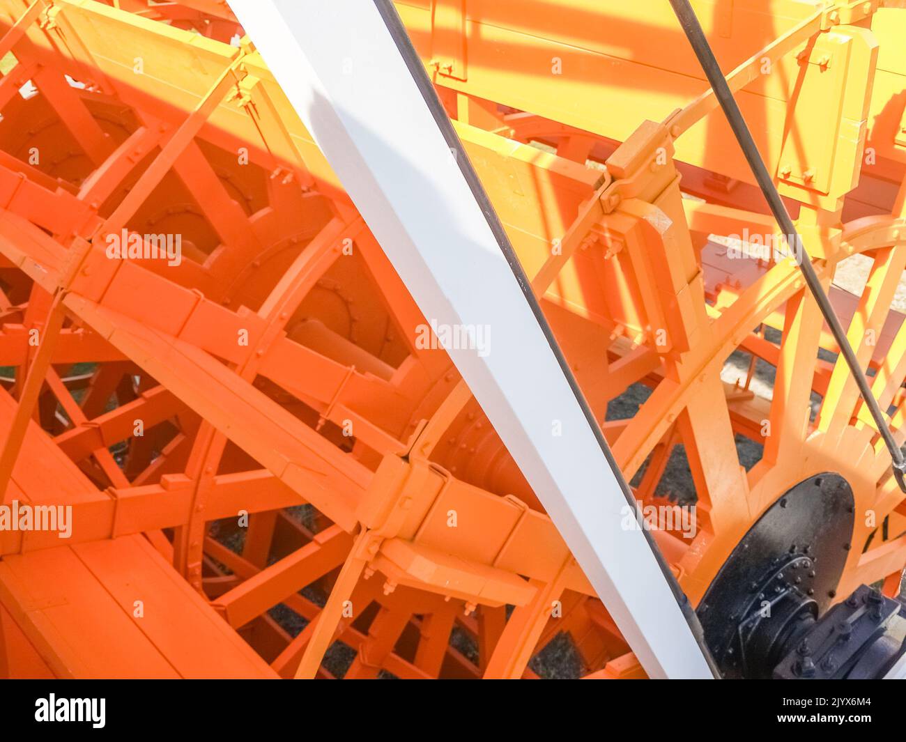 Ruota d'acqua in vecchio stile restaurata, mantenuta e dipinta da vicino in giallo. Foto Stock