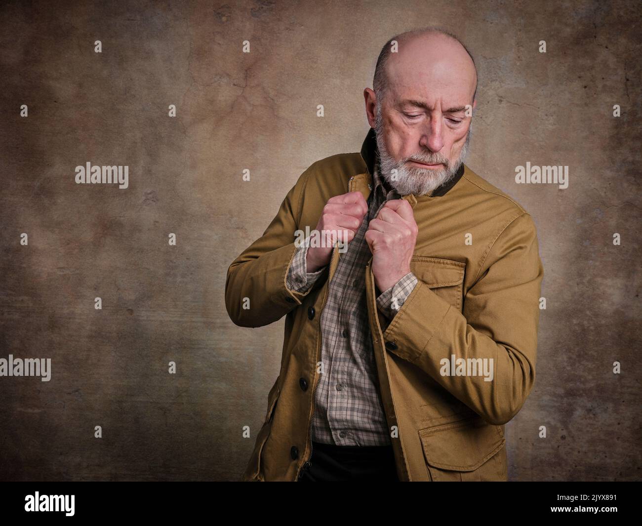 casual studio ritratto di un uomo anziano bearded in pensiero profondo o contemplazione contro grunge muro Foto Stock