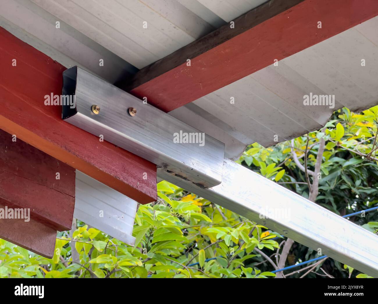 Il tubo rettangolare in acciaio al carbonio ha Unito la trave in legno del tetto della casa per estensione tenda, vista frontale con il copy space. Foto Stock