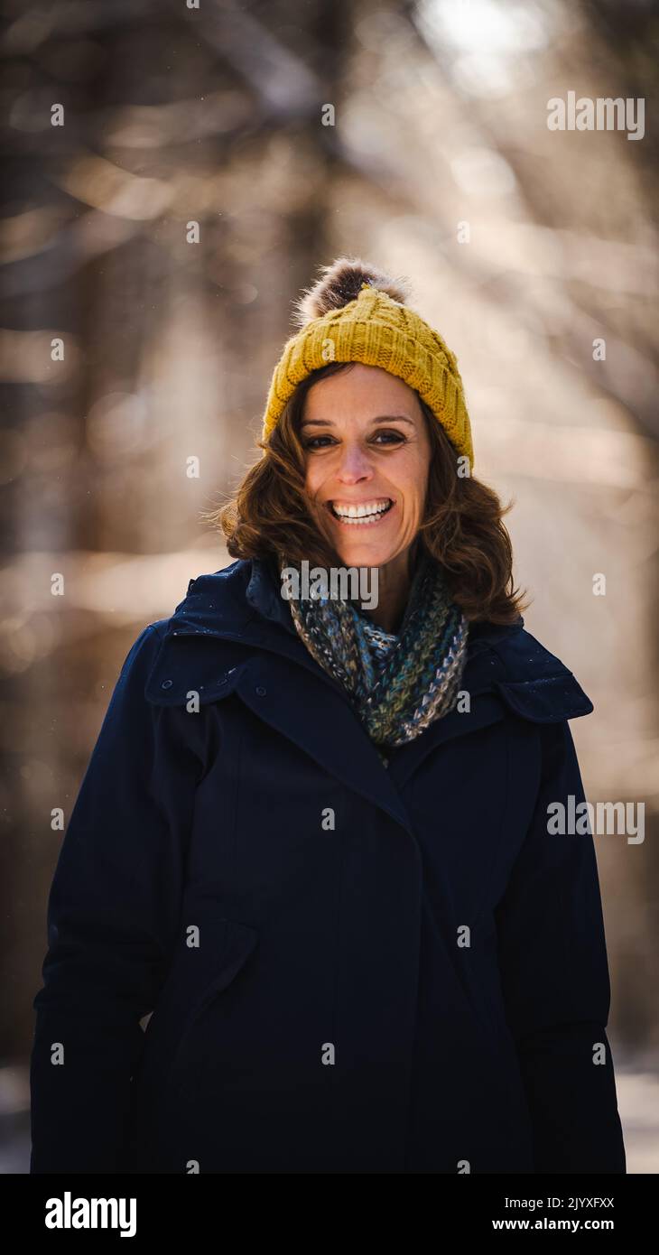 Una donna caucasica di mezza età che si gode un'escursione nei boschi durante l'inverno. Foto Stock