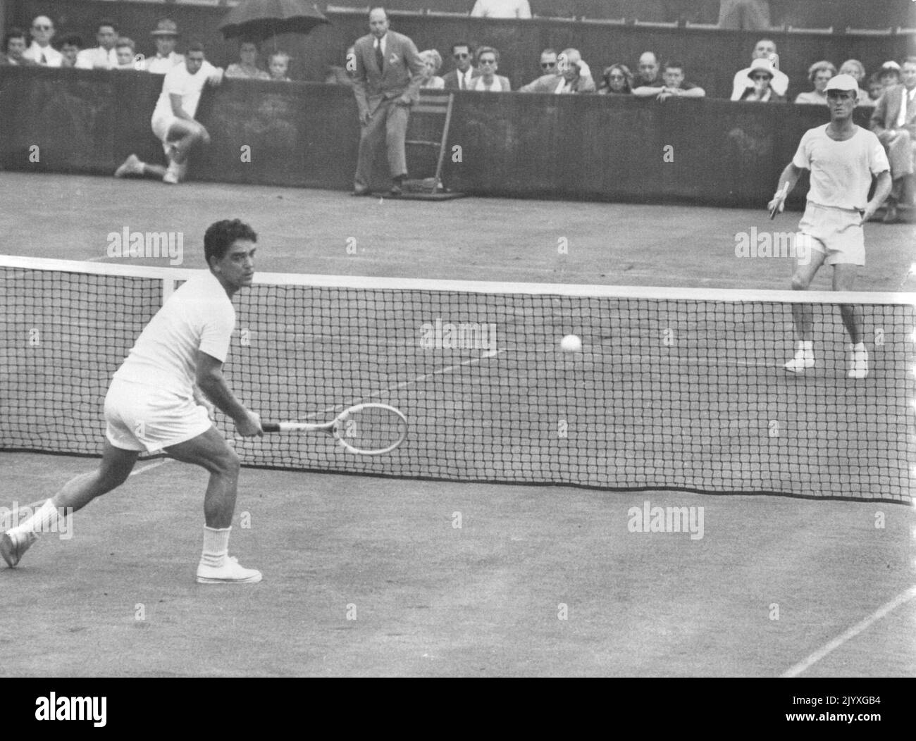 Sidwell Drives One Past Cucelli : Gianni Cucelli (Forecourt), campione italiano, guarda in modo fortuito alla palla che Bill Sidwell (far Court) dell'Australia ha appena guidato nel secondo set della loro partita di tennis della Coppa Davis interzona a Rye, New York, 12 agosto. La pioggia ha interrotto la partita dopo che Sidwell aveva preso i primi due set, 6-2, 6-4. Settembre 06, 1949. Foto Stock