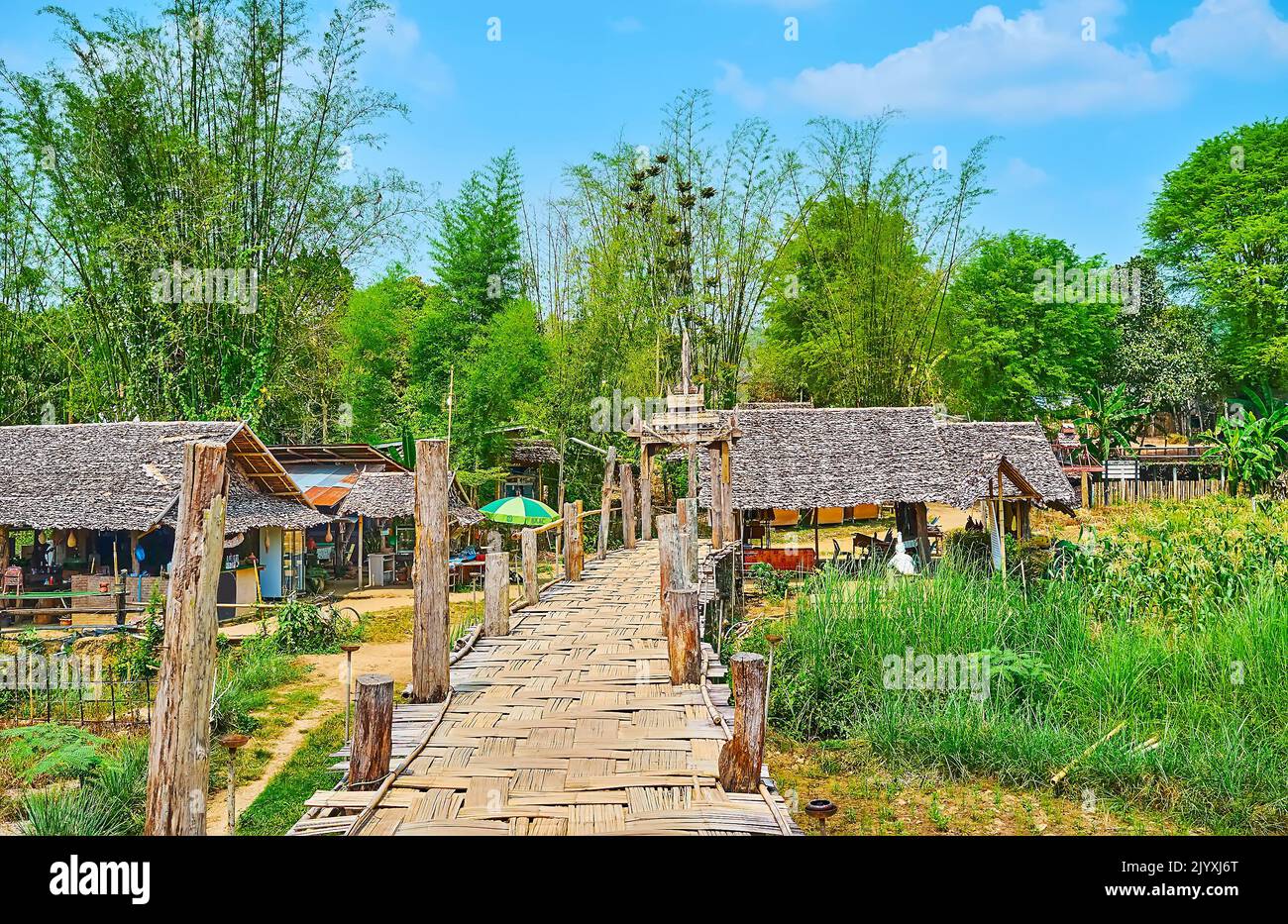 Il villaggio capanne in legno, circondato da addensi di bambù e con su Tong Pae Bamboo Bridge in primo piano, Mae Hong Son sobborgo, Thailandia Foto Stock