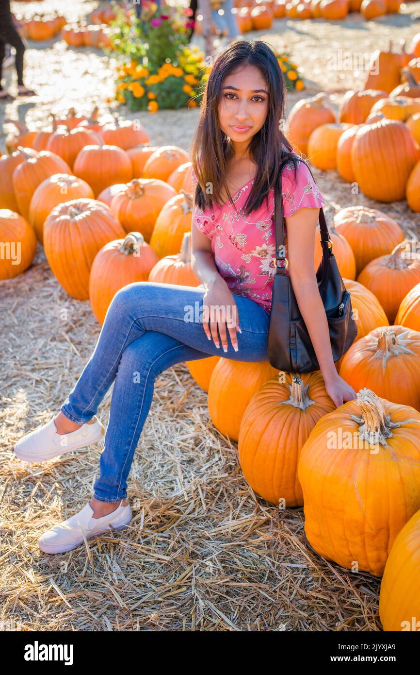 Ritratto di festa di Autunno di una giovane donna asiatica seduta in un campo di Pumpkins Foto Stock