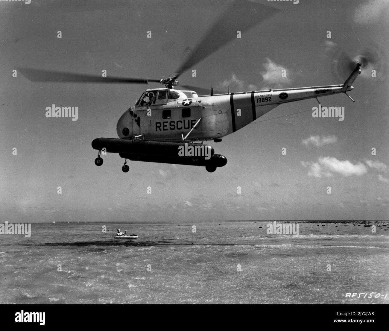 L'elicottero Okinawa simula il salvataggio in mare -- sorvolando le calme acque poco profonde al largo di Okinawa, un elicottero di salvataggio H-19 dell'aeronautica statunitense del 2nd si prepara a raccogliere una "vittima di un incidente" in un tentativo di salvataggio simulato. Il gigantesco-rotored aereo è gestito abilmente da piloti ben addestrati in tutte le operazioni di salvataggio, perché gli elicotteri sono costosi e venti difficili a basse quote potrebbe causare la perdita sia di pilota e aereo. Oltre al volo e alla manutenzione di elicotteri di tipo H-19, il 2nd Air Rescue Group, sempre in allerta per le emergenze che coinvolgono soccorsi, anche flie Foto Stock