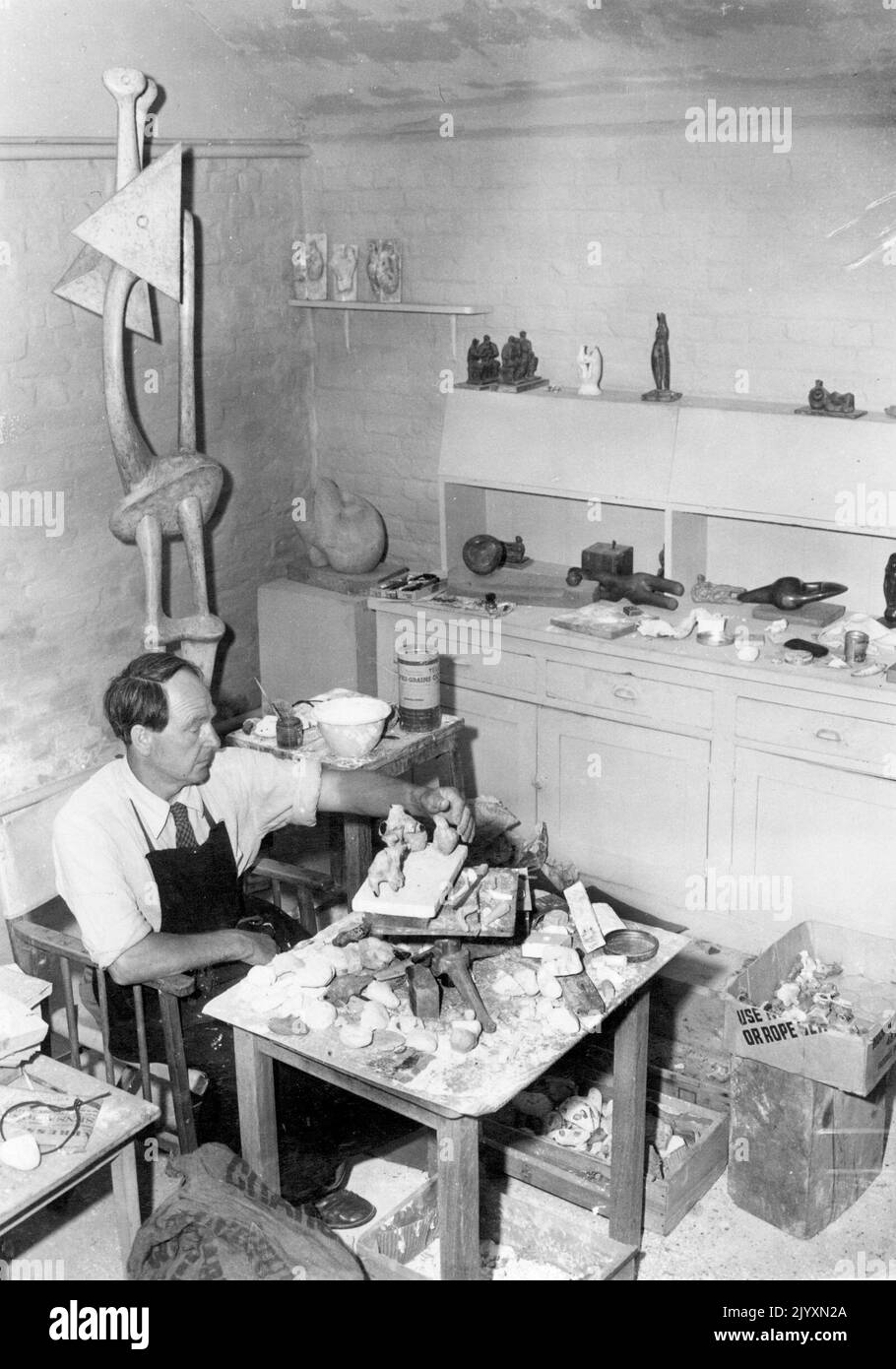 Henry Moore, scultore -- scultore Henry Moore, al lavoro nel suo studio, studia pietre di forme strane e fantastiche che raccoglieva durante le vacanze a Broadstairs, Kent, con idee per le sue creazioni. Gennaio 1, 1952. Foto Stock