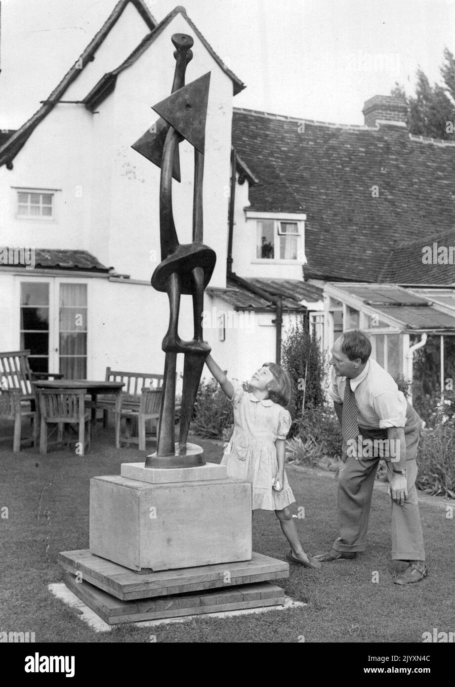 Henry Moore, scultore -- Henry Moore nel giardino della sua casa di campagna - 'Hogland'. Sullo sfondo è il cottage del 15th ° secolo in cui vive. Con lo scultore è Maria, sua figlia di 6 anni. Gennaio 1, 1952. Foto Stock