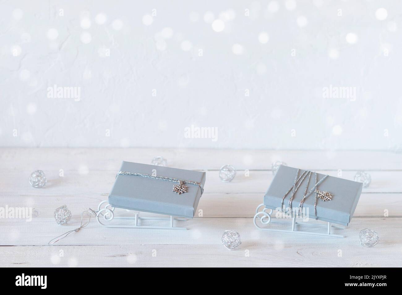 Piccole slitte decorative con scatole regalo di Natale grigie, colori bianco, grigio e argento, spazio copia, idea per il biglietto di Natale Foto Stock