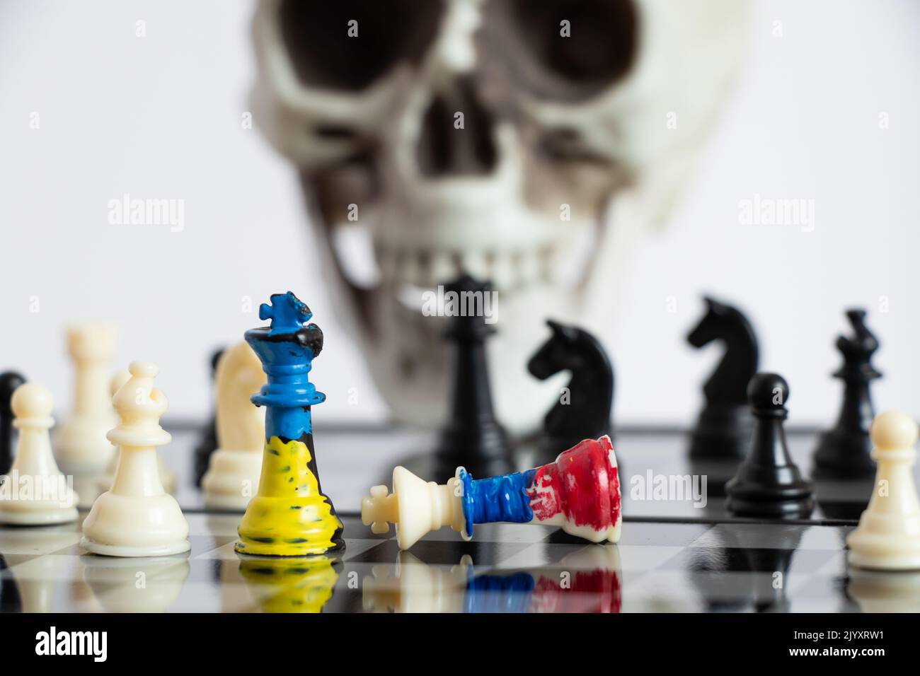 Scacchi con una bandiera dipinta di Russia e Ucraina su una scacchiera e una testa di uno scheletro sullo sfondo, una partita di morte tra i due paesi di Foto Stock
