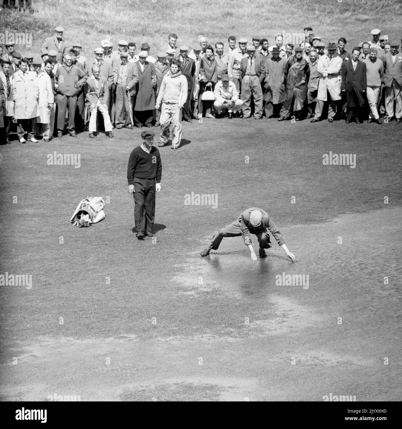 1961: Foto del file datata 1961 luglio del golfista americano Arnold Palmer che guarda il suo pesce caddie per la sua palla in una delle grandi piscine d'acqua lasciate da pioggia notturna sul sesto fairway del campo da golf Royal Birkdale, Lancashire. Data di emissione: Giovedì 8 settembre 2022. Foto Stock