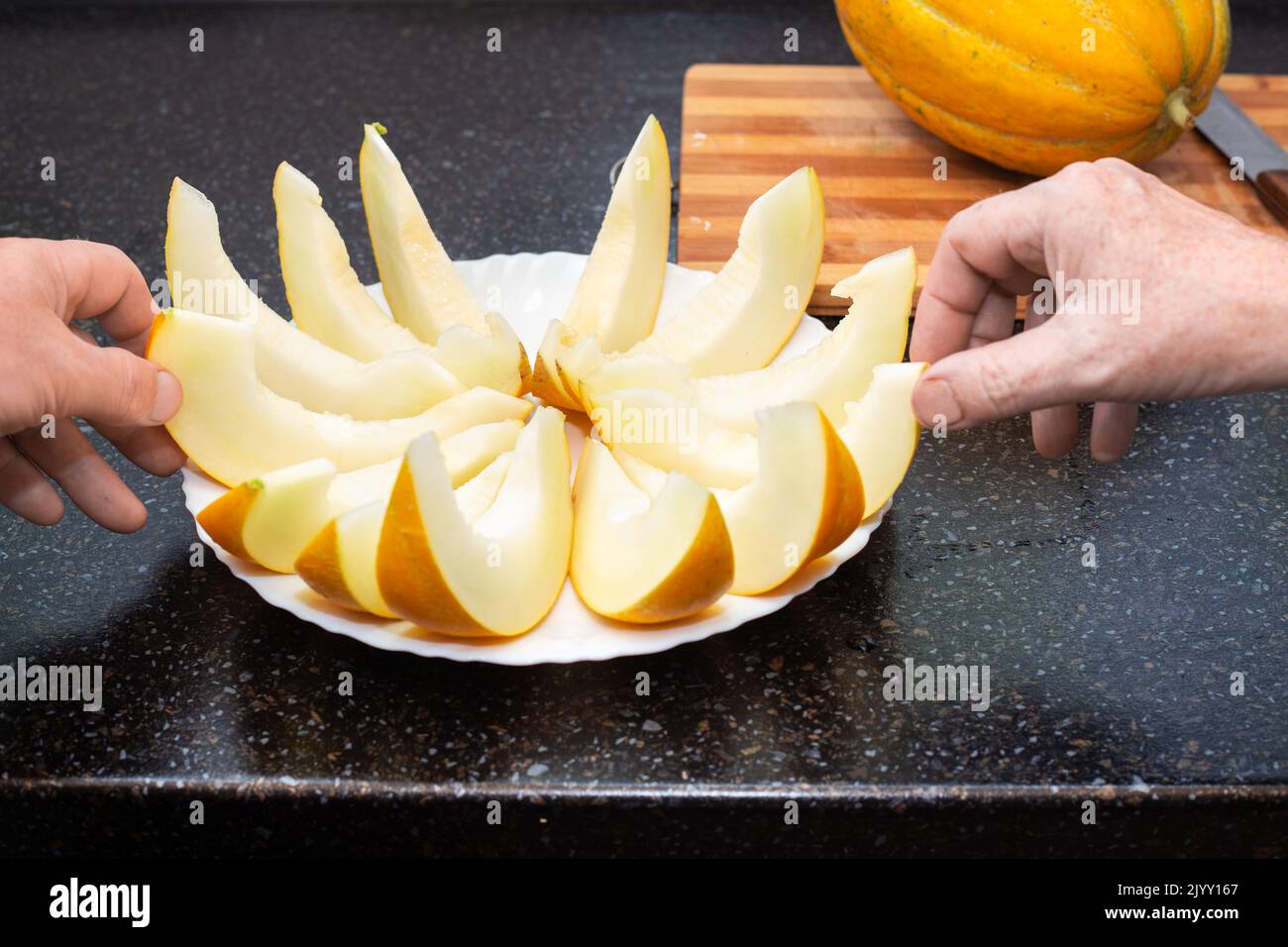 Le persone prendono fette di melone maturo succosa affettate dal piatto con le mani. Delizioso cibo sano. Foto Stock