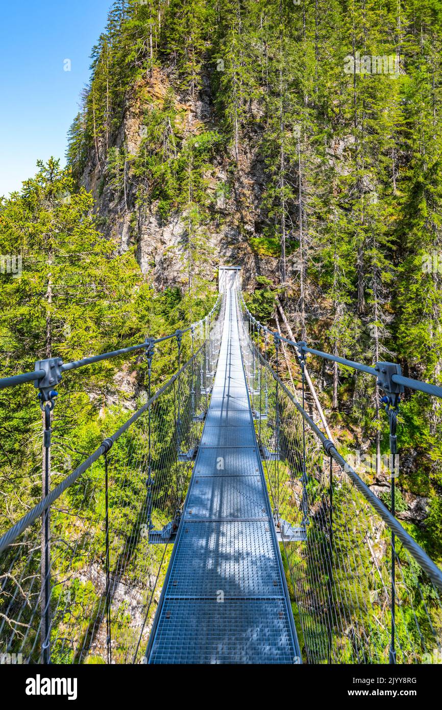 Semplice ponte sospeso sulla valle di montagna Foto Stock