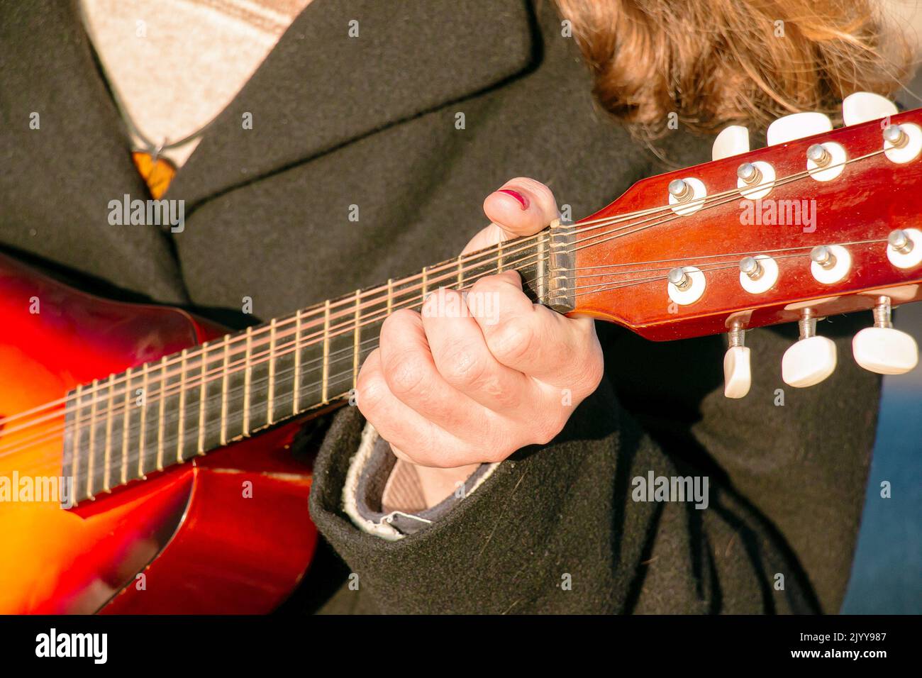 Un giovane gioca il mandolino in città per strada. Mani ravvicinate. Foto Stock