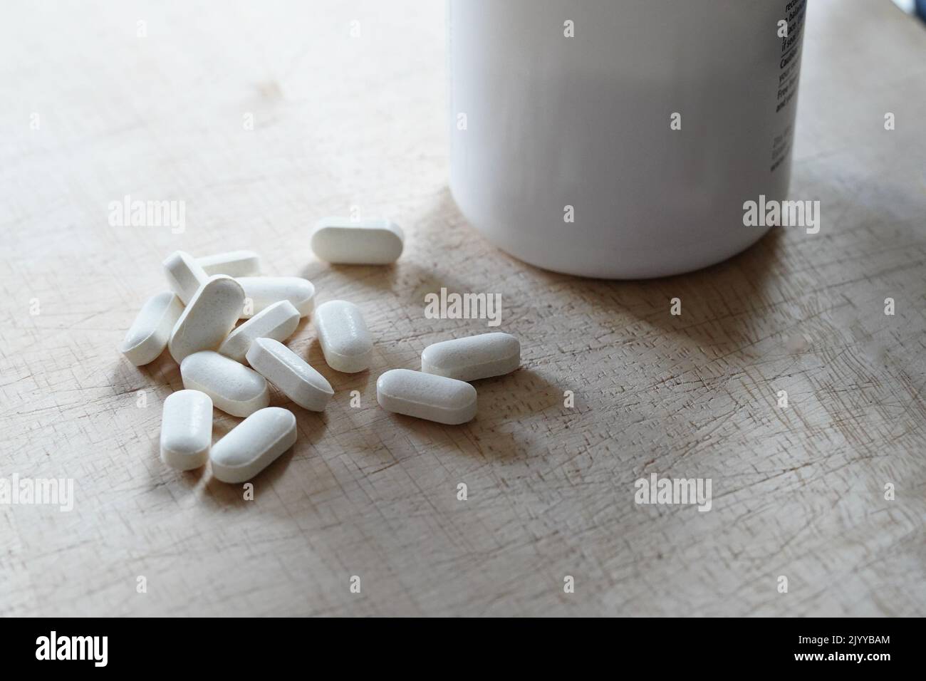 Medicina di plastica o vitamine bottiglia e capsule bianche pillole fuori, medicina e concetto di salute. Illustrazione di epidemie di oppioidi Foto Stock
