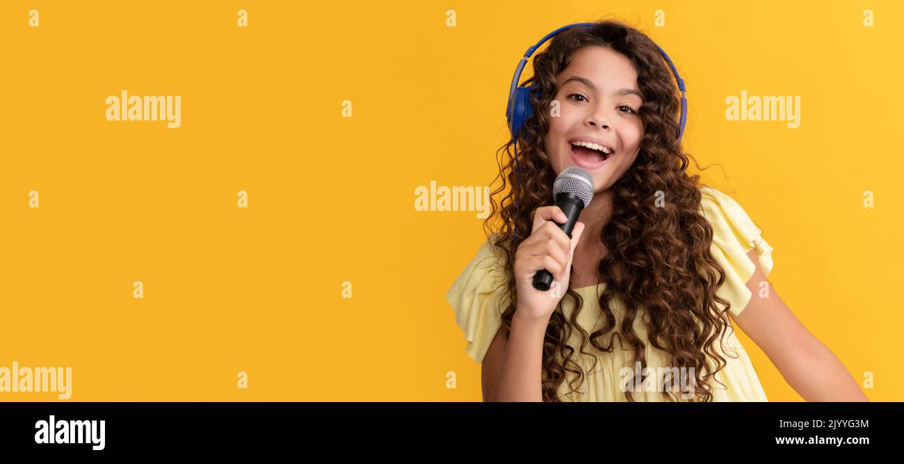 cantante bambino che canta karaoke nel microfono. formazione vocale online. Ritratto per bambini con cuffie, poster orizzontale. Ragazza che ascolta musica, banner Foto Stock