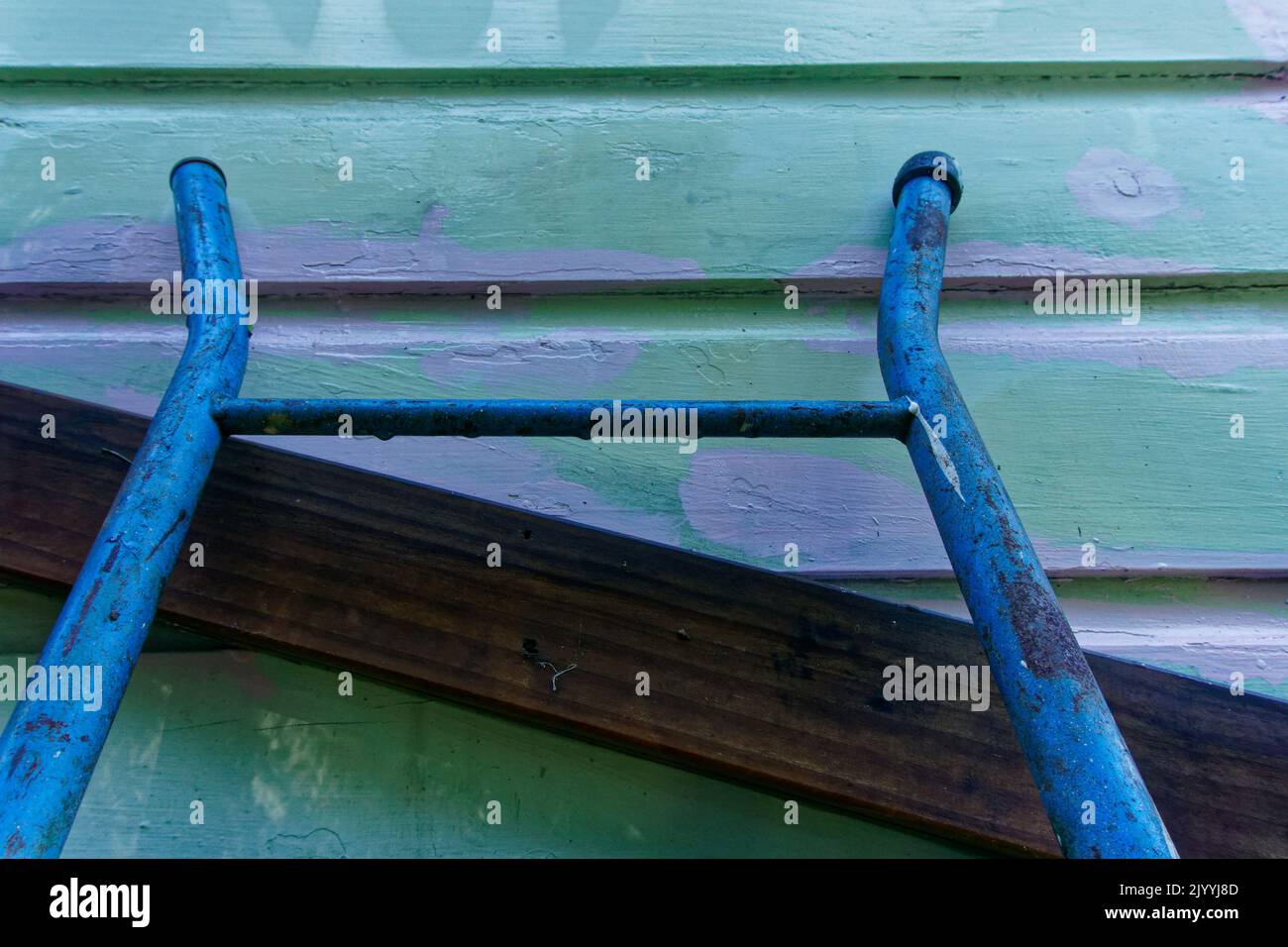 Scala blu appoggiata ad una parete di legno che è stata dipinta con primer, ristrutturando e mantenendo una vecchia villa o bungalow Kiwi in legno. Foto Stock