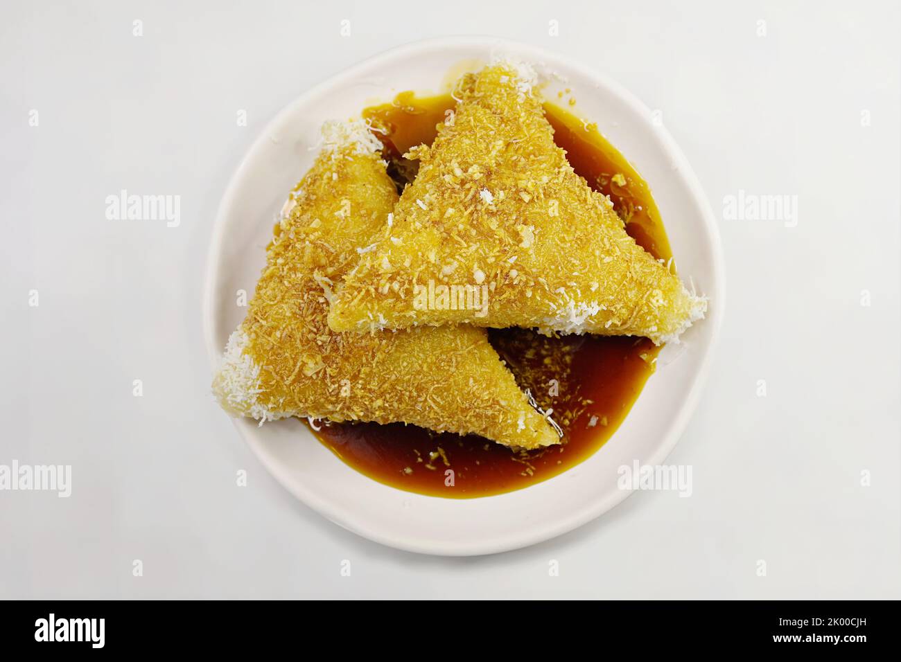 Gnocchi di riso appiccicosi tradizionali di Kueh Lopes, serviti con scaglie di cocco grattugiate fresche e sgocciolate con sciroppo di zucchero di palma marrone o melaka di gula Foto Stock