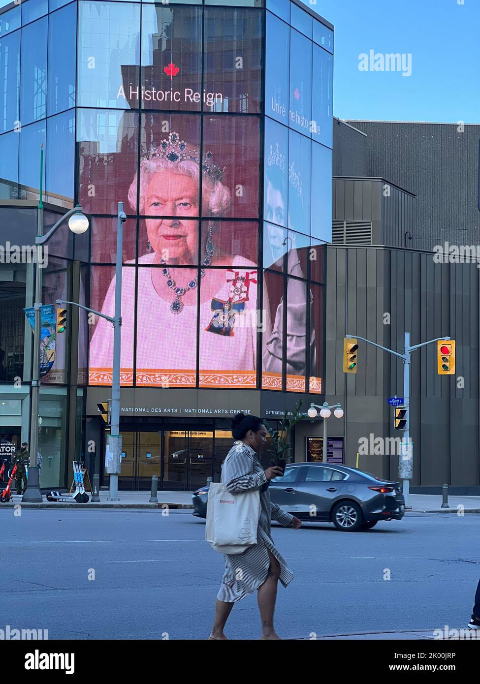 Ottawa. 8th Set, 2022. Un passeggero cammina accanto a uno schermo a LED che mostra un'immagine enorme della regina Elisabetta II al National Arts Centre di Ottawa, Canada, il 8 settembre 2022. La regina Elisabetta II, il monarca più longevo della storia britannica, è morta a 96 anni, Buckingham Palace ha annunciato giovedì. Credit: Notizie dal vivo min Chen/Xinhua/Alamy Foto Stock