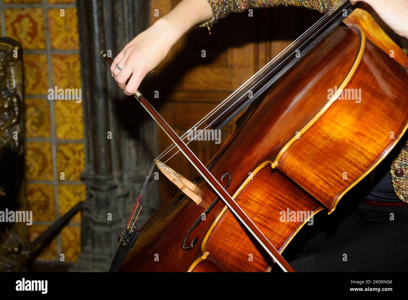 Primo piano di una donna che suona violoncello contro un vecchio muro Foto Stock