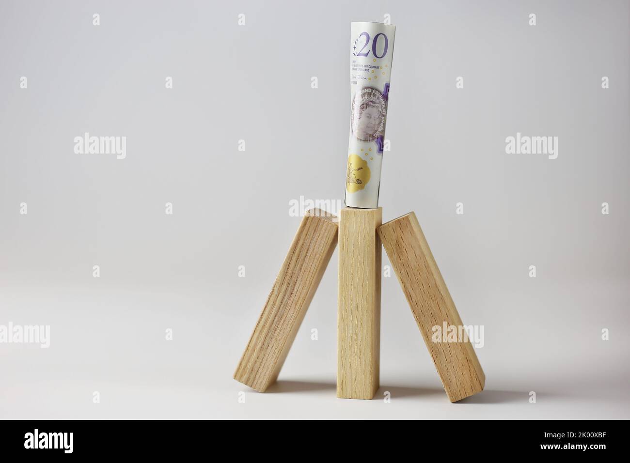 Le sterline inglesi arrotolate si erborrano su cubi di legno su uno sfondo isolato e chiaro Foto Stock