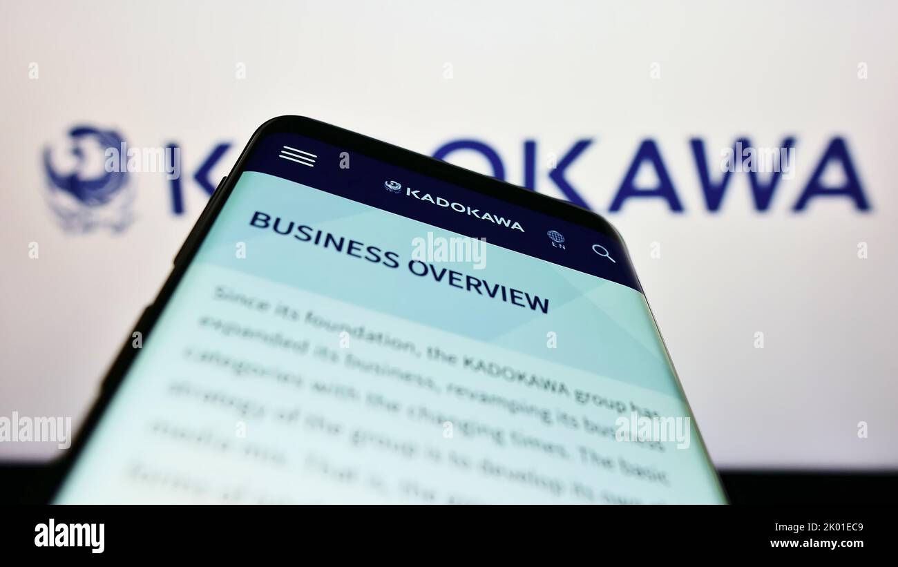 Smartphone con sito Web della società di media giapponese Kadokawa Corporation sullo schermo di fronte al logo aziendale. Messa a fuoco in alto a sinistra del display del telefono. Foto Stock