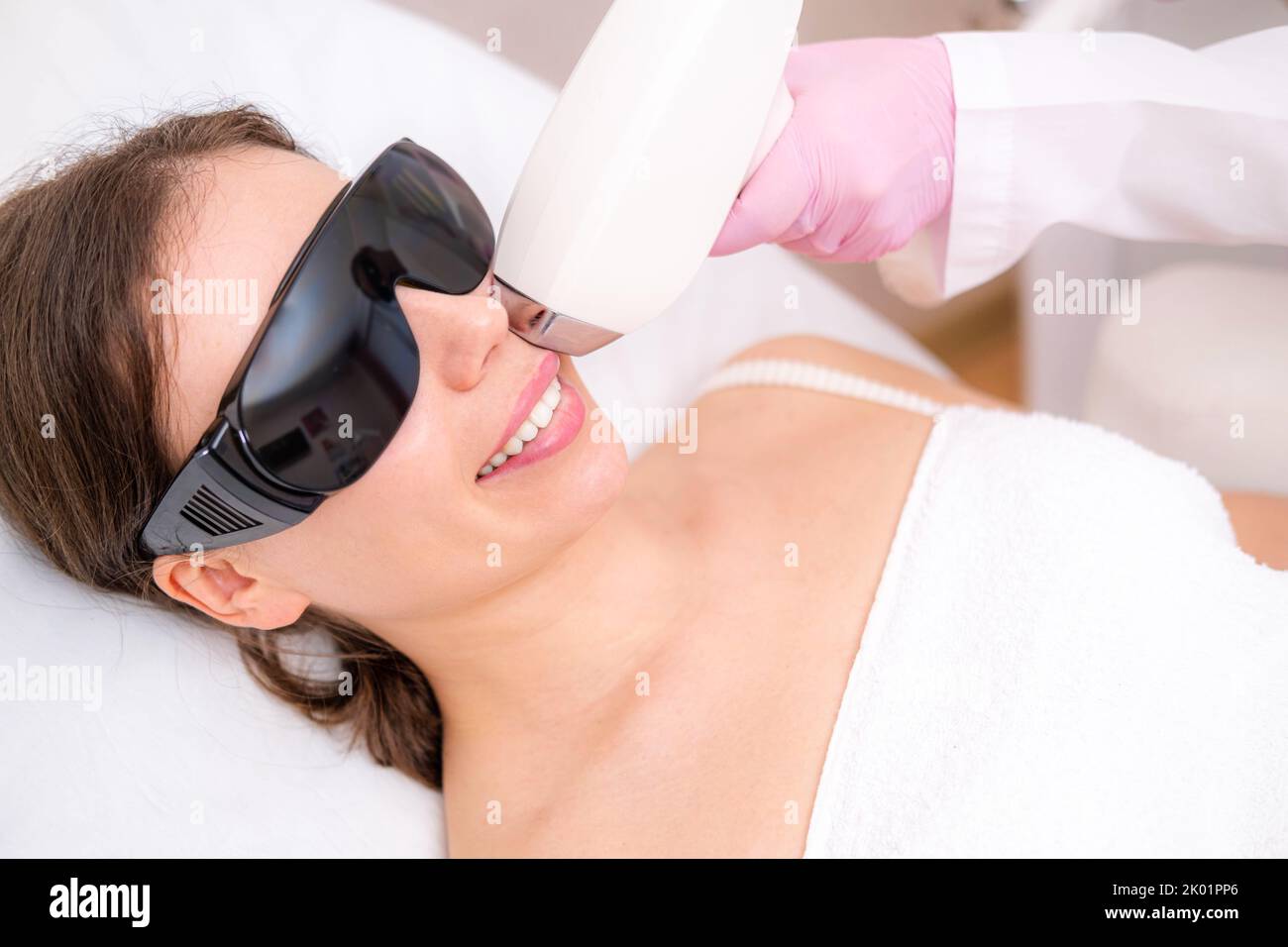 Depilazione laser a diodi, Beautician rimuove i capelli sulla bella faccia femminile, depilazione per la pelle liscia, procedura laser in studio di bellezza o clinica Foto Stock