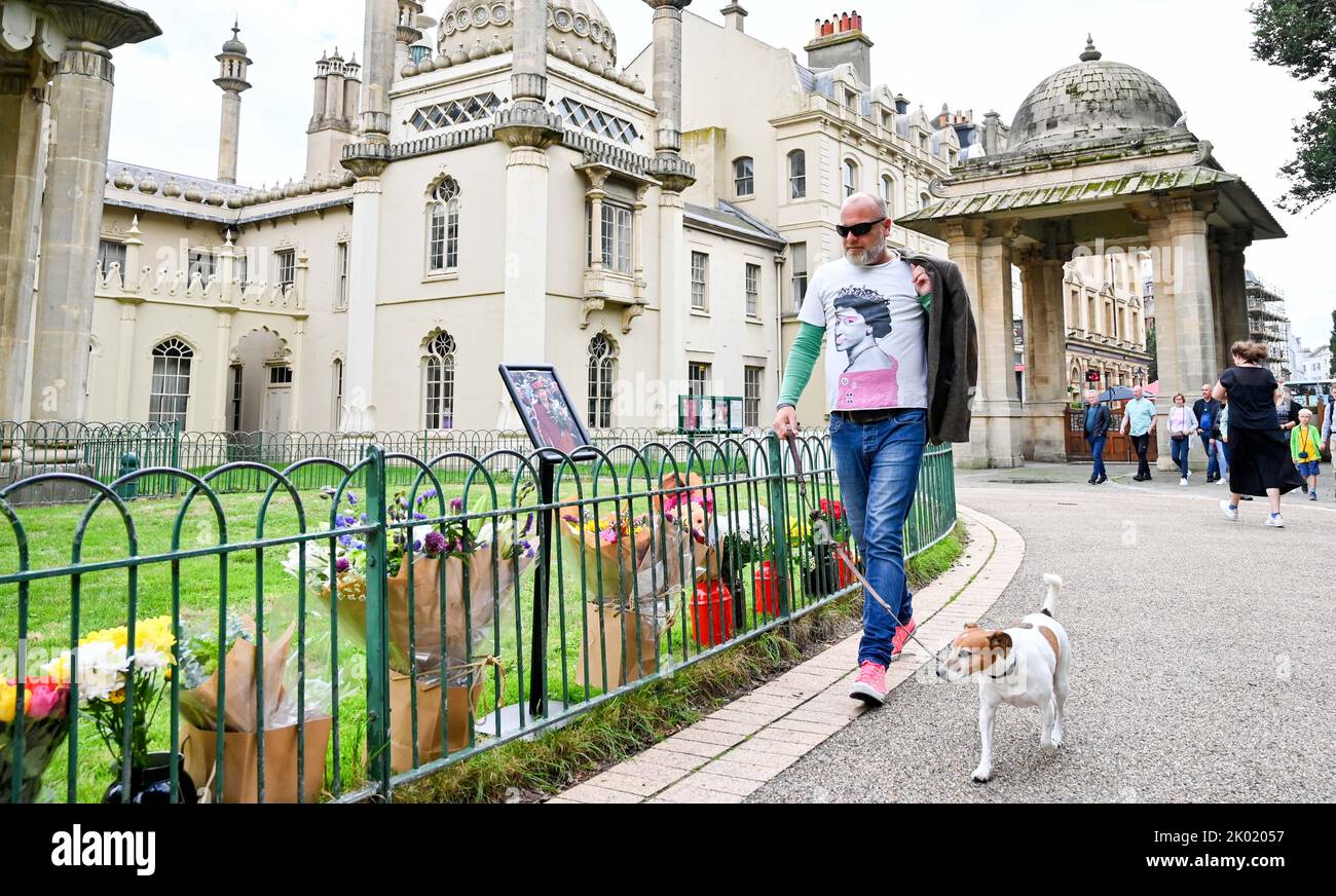 Brighton UK 9th settembre 2022 - Un membro del pubblico che indossa una maglietta della Regina passa per tributi floreali alla Regina al di fuori del Padiglione reale di Brighton oggi dopo la sua morte all'età di 96 anni è stato annunciato ieri . Elisabetta II regnò come monarca britannico per 70 anni : Credit Simon Dack / Alamy Live News Foto Stock