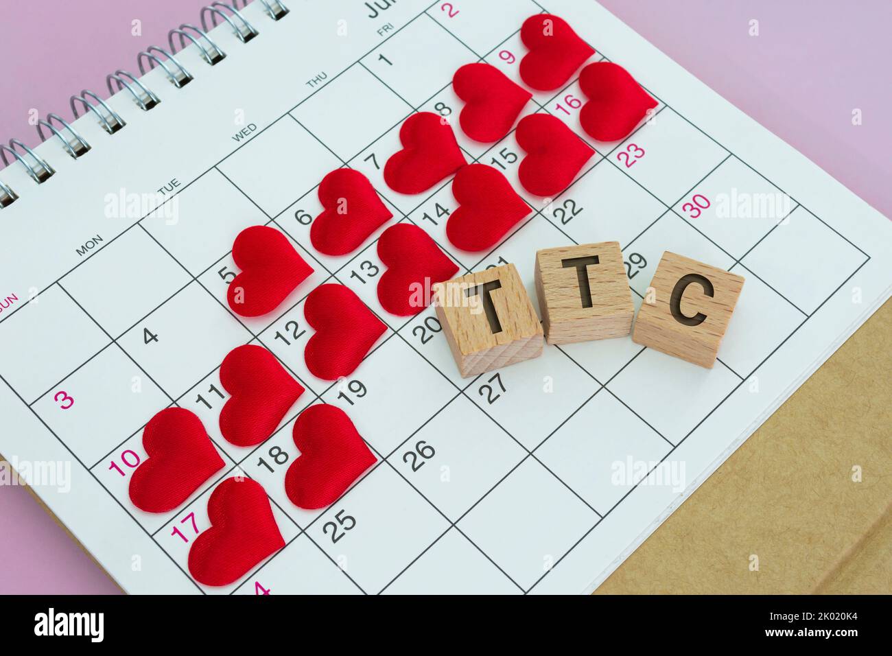 Parola TCC su blocco di legno con forma a cuore rosso sul calendario. Sopravvivere alle due settimane di attesa quando si sta cercando di concepire. Foto Stock