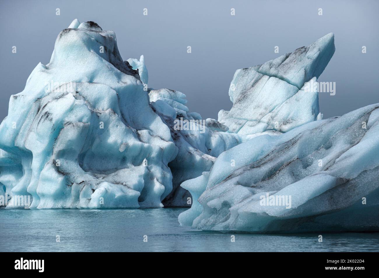 Gli iceberg che si sono staccati dal ghiacciaio Breidamerkurjokull che galleggiano verso il mare nella laguna glaciale di Jokulsarlon, Islanda Foto Stock
