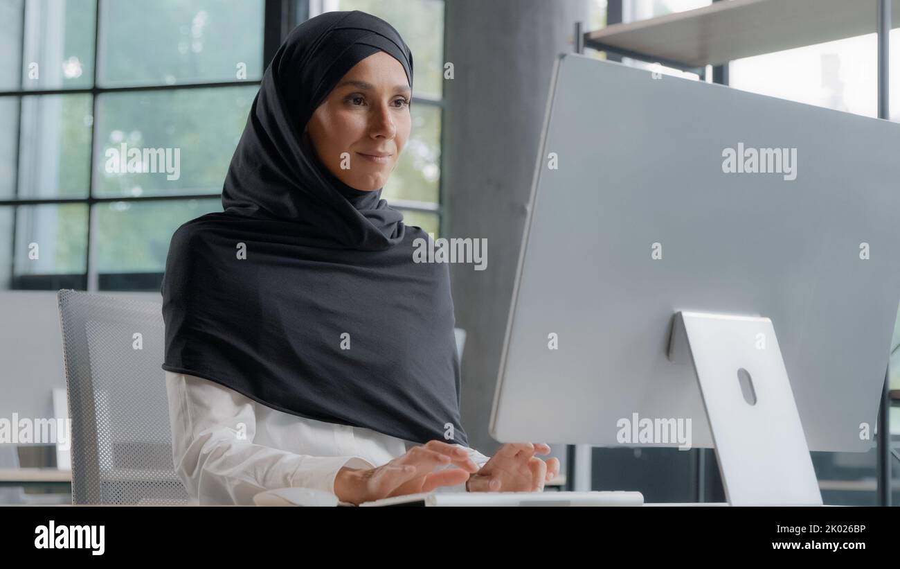 Giovane donna d'affari araba in hijab che lavora al computer sorridendo godendo lavoro d'ufficio donna di successo professionale manager azienda dipendente sviluppa Foto Stock