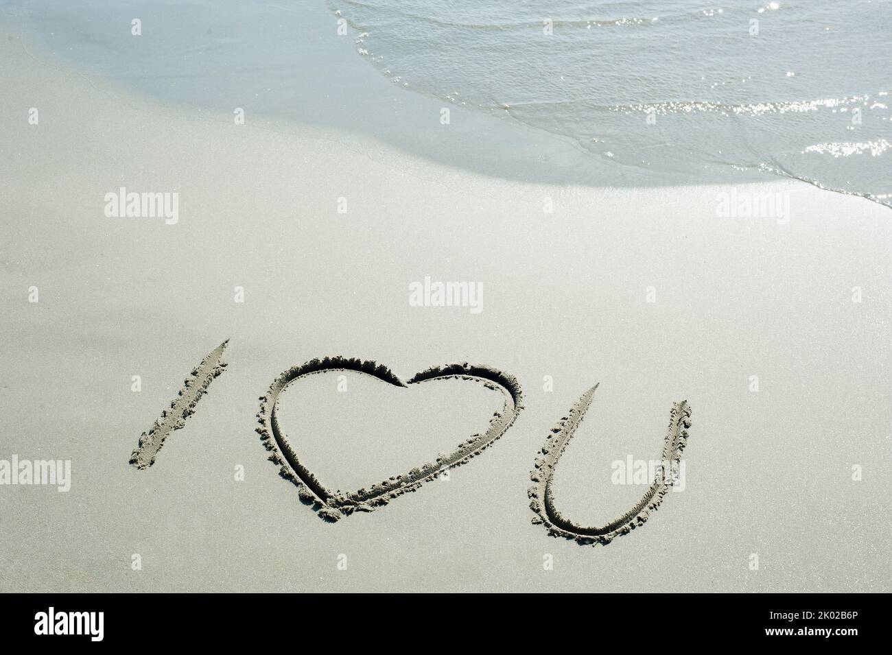 Concetto o concettuale ti amo testo scritto a mano in sabbia su una spiaggia con onde in un'isola esotica per amore, romanticismo, estate, mare, oceano, corsa, h Foto Stock